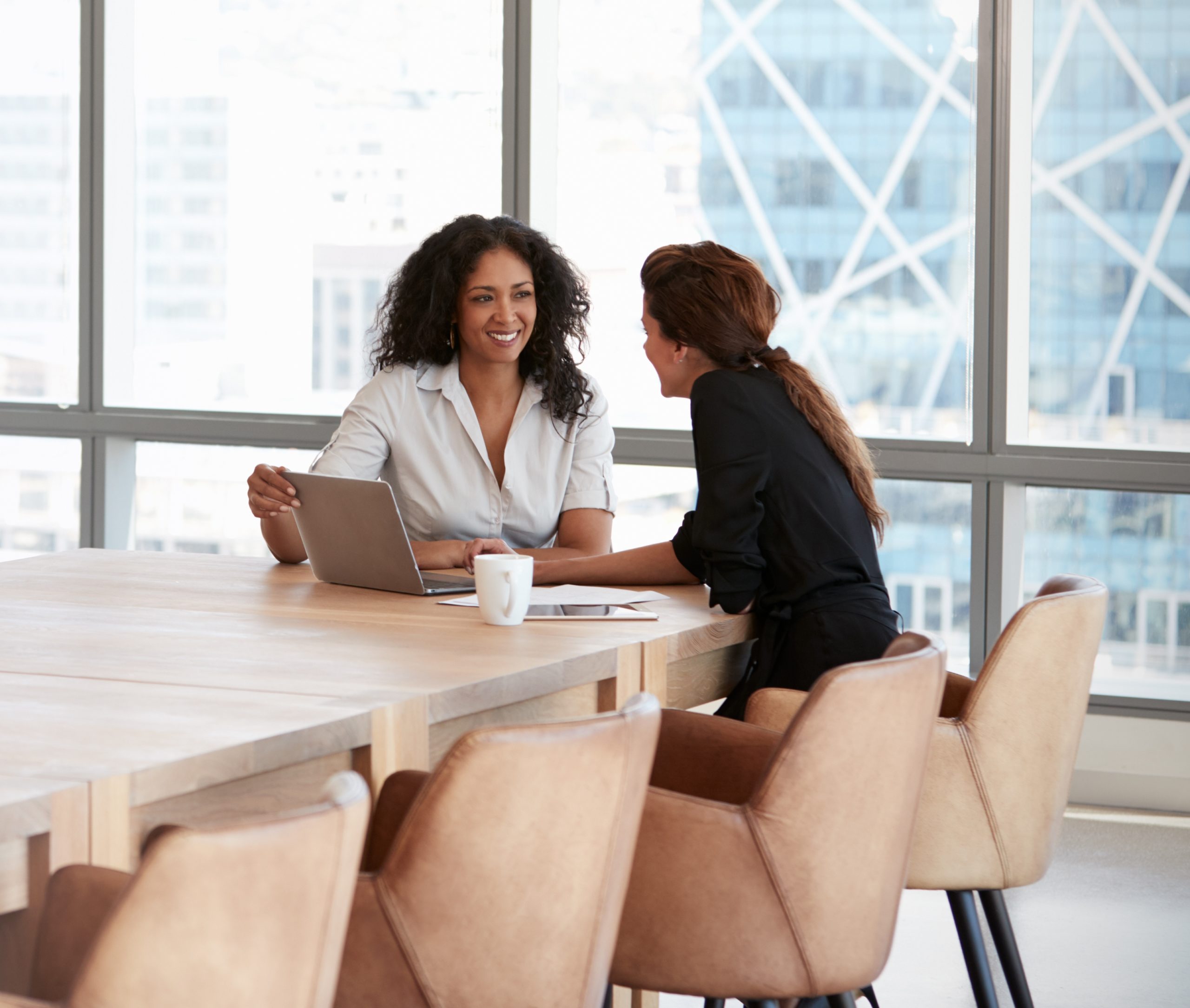 Two Women Speaking at an Office Conference Room Table