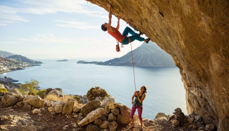 Woman supporting a man who's rock climbing