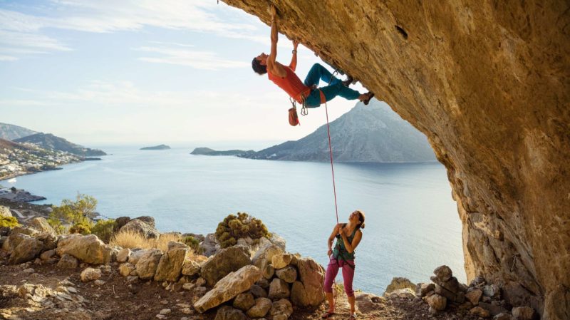 Woman supporting a man who's rock climbing