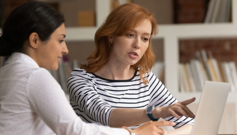 Two women reviewing content on a laptop