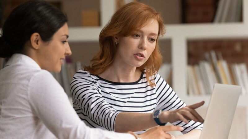 Two women reviewing content on a laptop