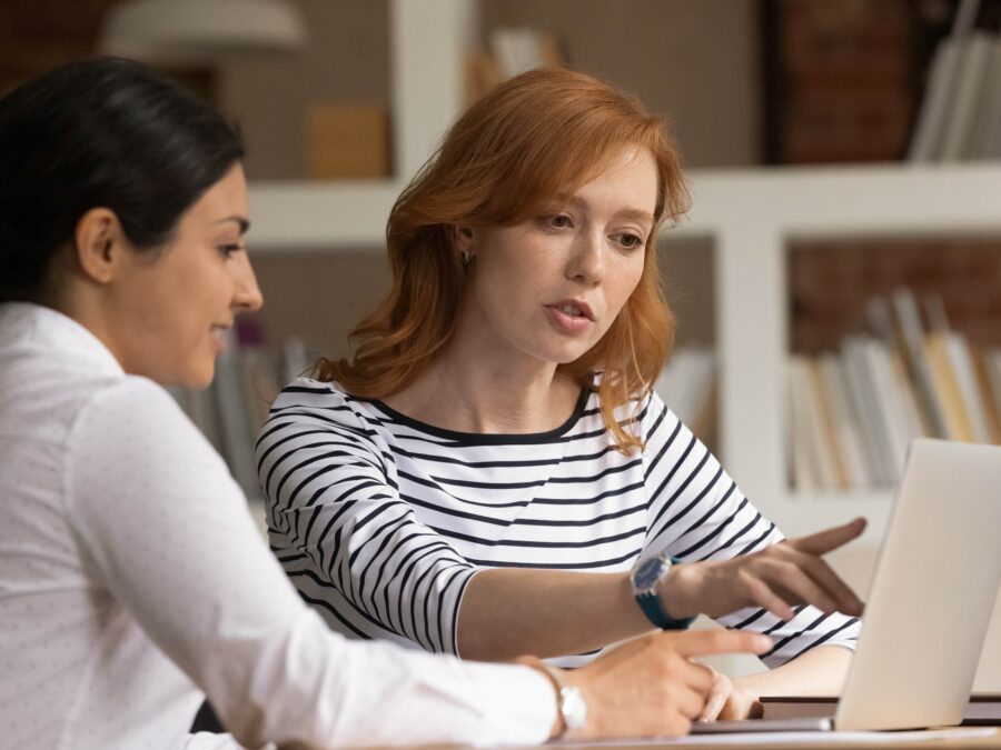 Two women discussing content on a laptop