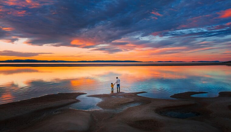 Two people stand at the edge of a body of water