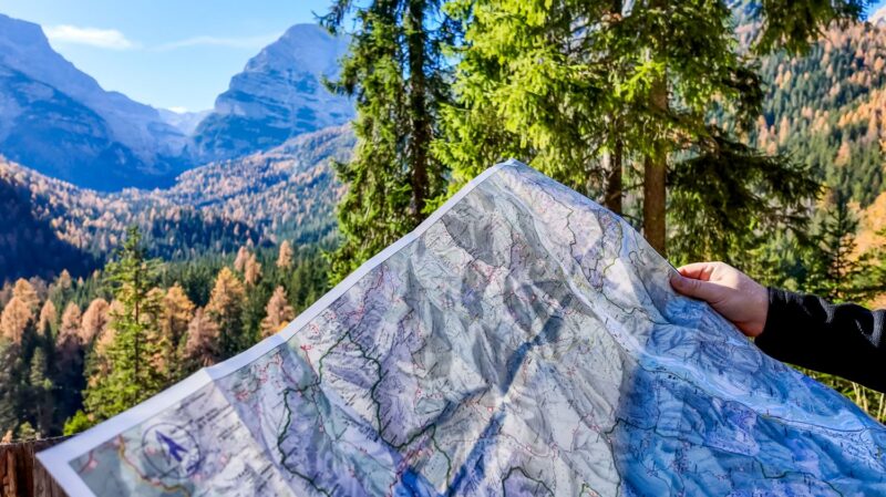 Paper map held up against a mountain landscape