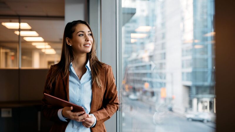 Woman thinking and looking out the window at work.