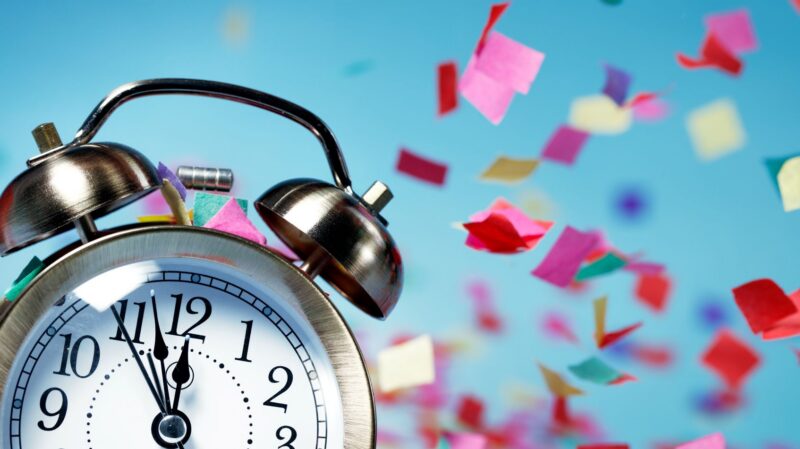 Alarm clock with colorful confetti around it.