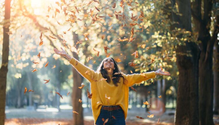 Woman walking through falling autumn leaves