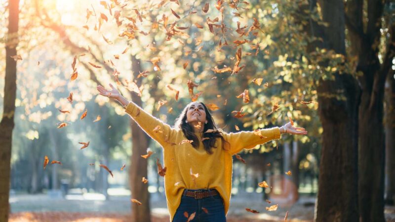 Woman walking through falling autumn leaves